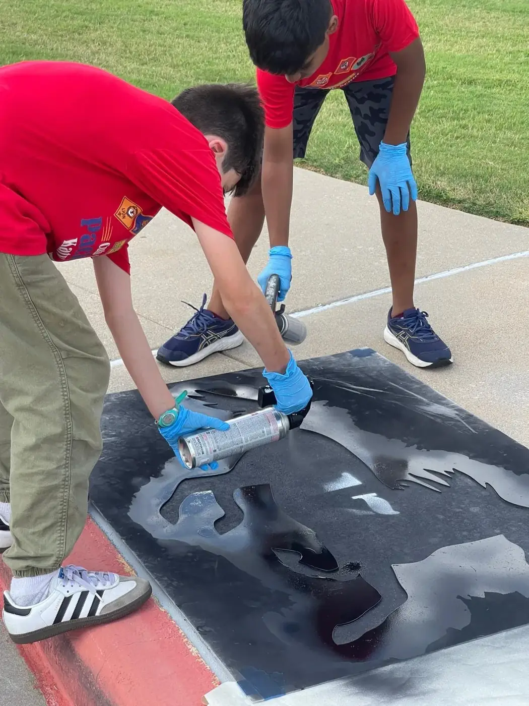 Pack 1103 scouts painting stencil murals at Stan C. Stanley Elementary